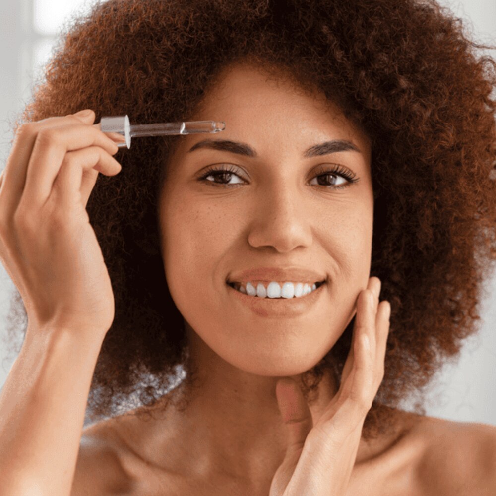 Applying facial oil to damp skin in morning light